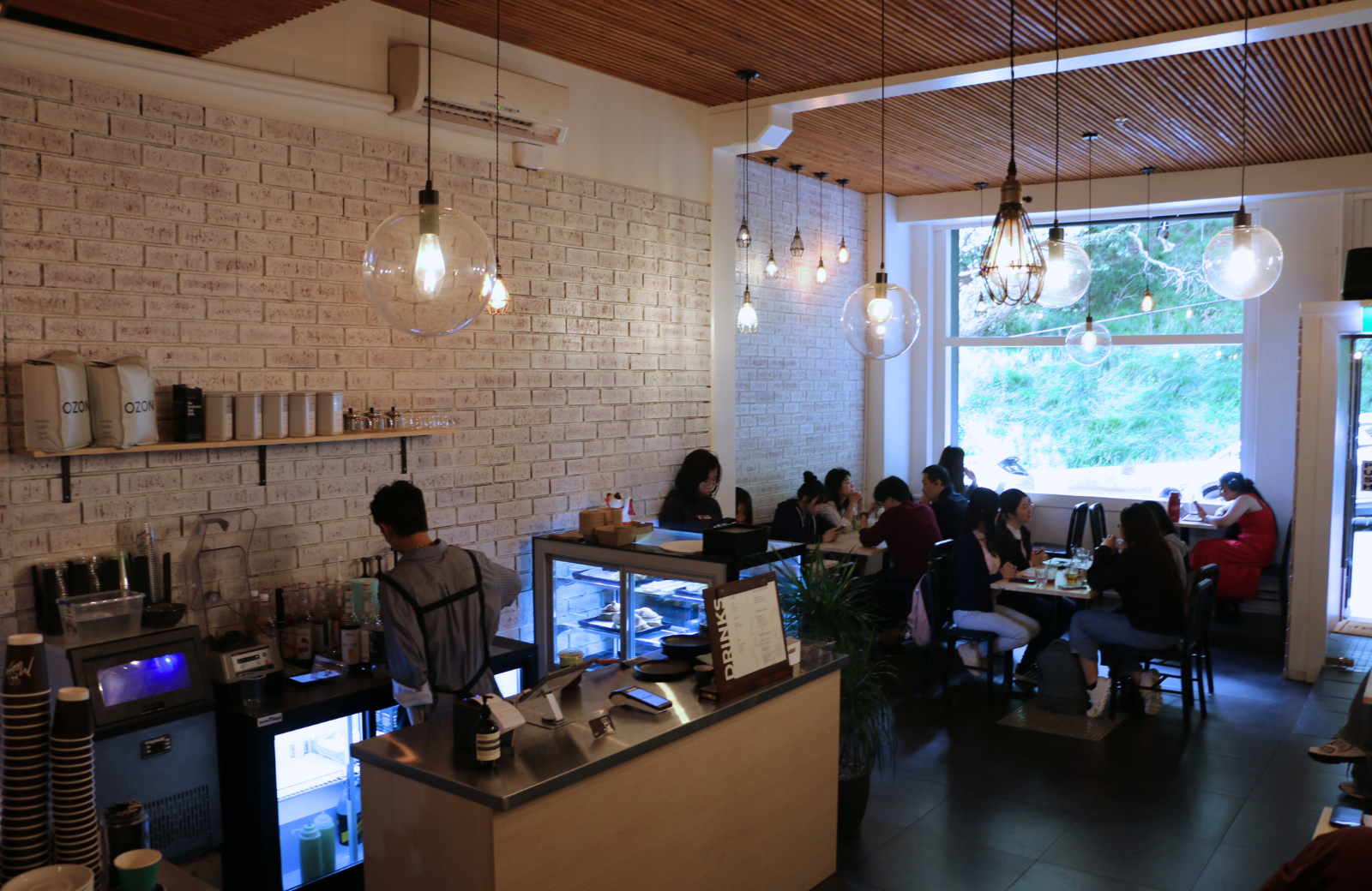 Inside Meeso Coffee with brick walls, pendant lights, and customers seated near the window.
